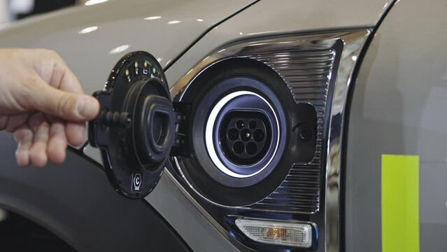 A male hand opens the charging port of an electrocar