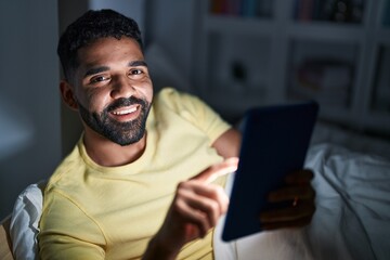 Young arab man using touchpad lying on bed at bedroom