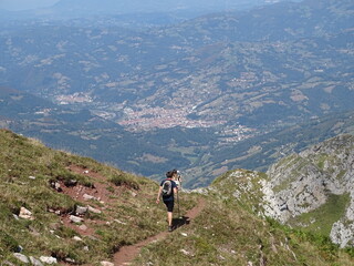 Fototapeta na wymiar Senderistas descendiendo de la montaña, muy a lo lejos el pueblo
