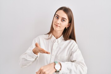 Young caucasian woman standing over isolated background in hurry pointing to watch time, impatience, upset and angry for deadline delay