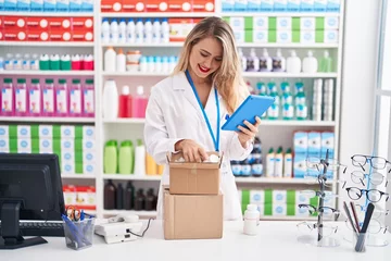 Foto op Canvas Young beautiful hispanic woman pharmacist using touchpad opening package at pharmacy © Krakenimages.com