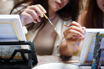 Close-up hand of young Asian teenage girls. holding a brush to paint a painting and intentionally...