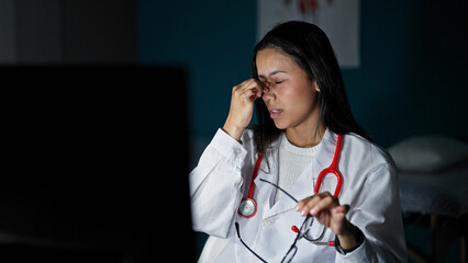 Young beautiful hispanic woman doctor stressed working taking out glasses at clinic