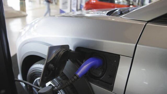 Silver colored electrocar on charge at the charging station indoors