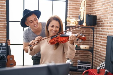 Man and woman musicians playing violin at music studio