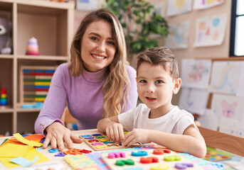 Fototapeta premium Woman and boy playing with maths puzzle game sitting on table at kindergarten