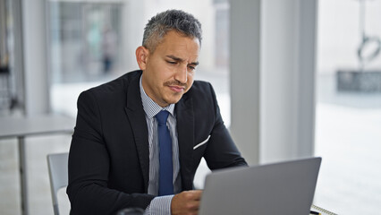 Young hispanic man business worker using laptop at office