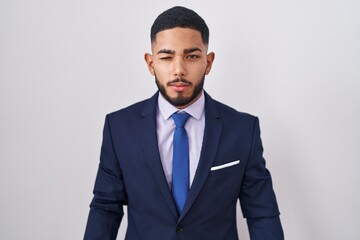 Young hispanic man wearing business suit and tie winking looking at the camera with sexy expression, cheerful and happy face.