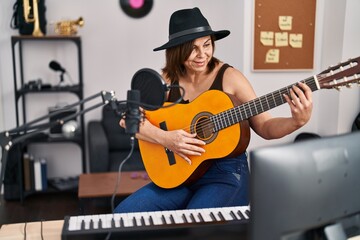 Middle age woman musician playing classical guitar at music studio