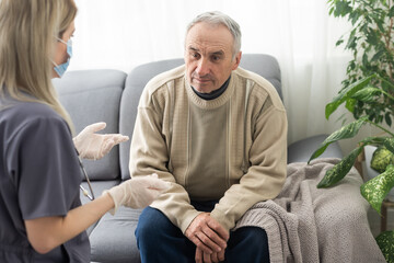 Portrait of mature female psychiatrist interviewing handicapped senior man during therapy session,...