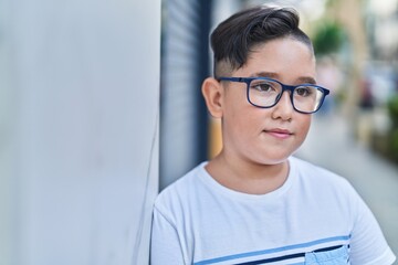 Adorable hispanic boy smiling confident looking to the side at street