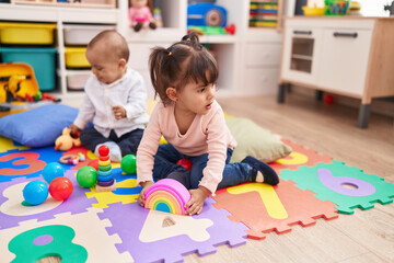 Adorable boy and girl sitting on floor playing at kindergarten