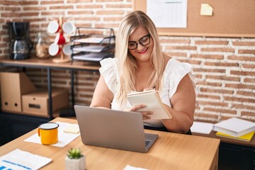 Young woman business worker using laptop writing on notebook at office