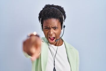 African american woman wearing call center agent headset pointing displeased and frustrated to the camera, angry and furious with you