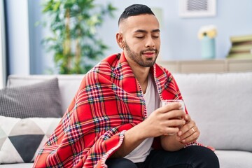 African american man drinking tea sitting on sofa at home