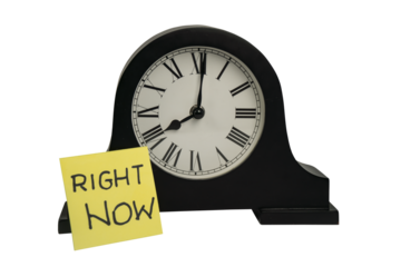 Stylowy zegar w czarnej obudowie z żółtą kartką z napisem: RIGHT NOW.