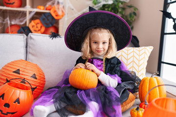 Adorable blonde girl wearing witch costume having halloween party at home