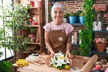 Middle age grey-haired woman florist make bouquet of flowers at florist