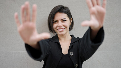 Young caucasian woman smiling doing frame gesture with hands over isolated white background