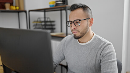 Hispanic man business worker using computer with serious face at office
