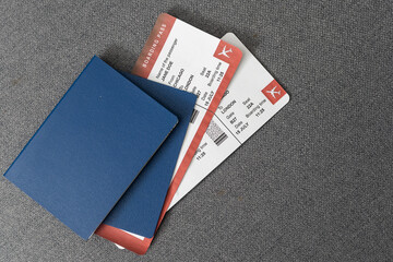 Two blue passports, green boarding pass, flight tickets gray background close up top view, airplane...