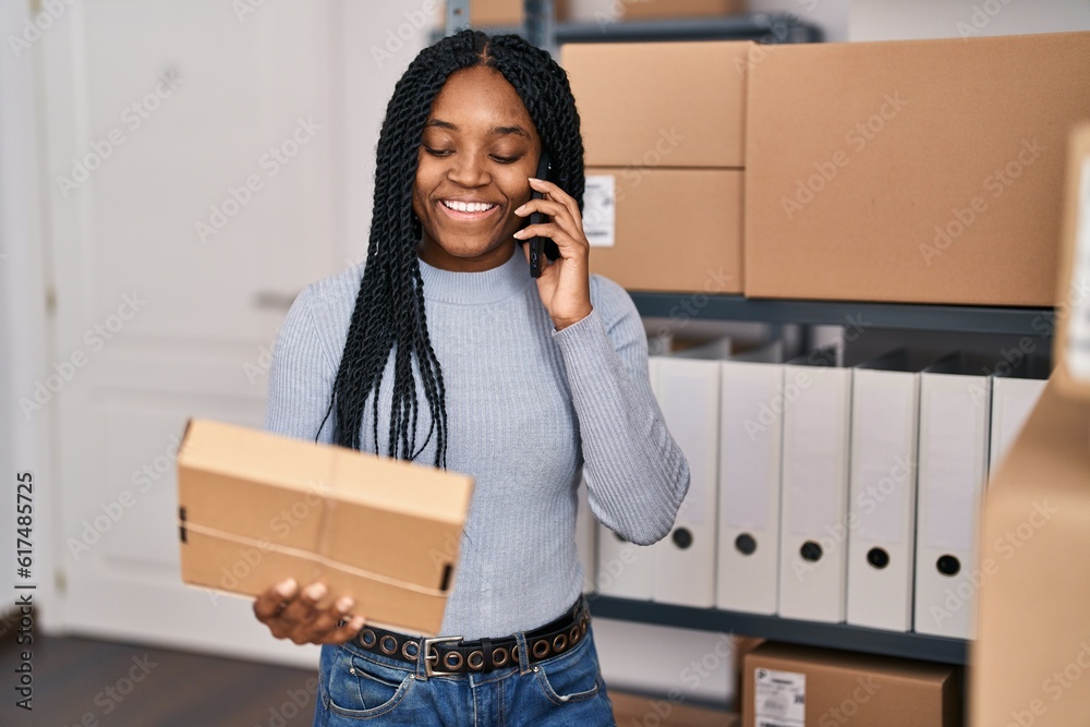 Poster African american woman ecommerce business worker talking on smartphone holding package at office