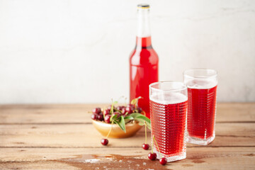 Boozy Refresing Cold Hard Cherry Cider in a Pint Glass and Bottle on wooden table. Copy space