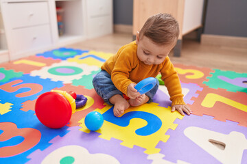 Adorable caucasian baby playing with hoops sitting on floor at kindergarten
