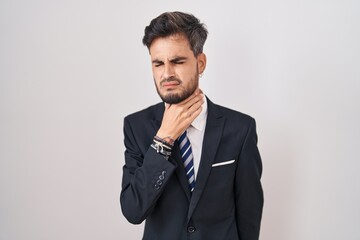 Young hispanic man with tattoos wearing business suit and tie touching painful neck, sore throat for flu, clod and infection