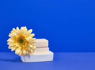 Natural soap lies on a soap dish with a beautiful bright flower. Copy space for text.