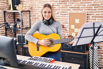 Young woman artist singing song playing classical guitar at music studio