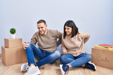 Young couple moving to a new home suffering of backache, touching back with hand, muscular pain