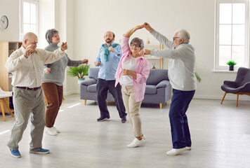 Full length portrait of a group of happy smiling senior people men and women having fun and dancing enjoying activities in retirement home together. Leisure time in nursing home concept.