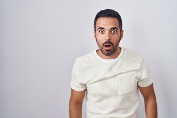 Hispanic man with beard standing over isolated background afraid and shocked with surprise and amazed expression, fear and excited face.