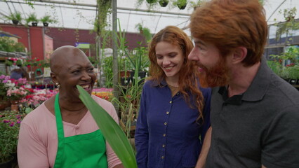 Naklejka premium Joyful Couple Shopping for Plants in Flower Shop with a Cheerful Laughing Black Employee