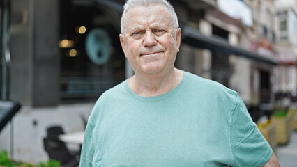 Middle age grey-haired man smiling confident standing at coffee shop terrace