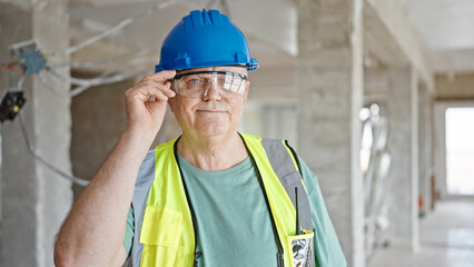 Middle age grey-haired man builder smiling confident standing at construction site