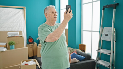 Middle age grey-haired man having video call at new home