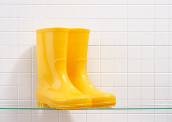 Gardening concept. Yellow rubber boots on a white tile background. Copy space for text.