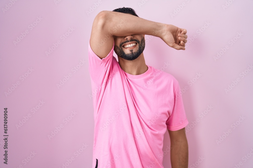 Canvas Prints hispanic young man standing over pink background covering eyes with arm smiling cheerful and funny. 