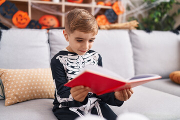 Adorable hispanic boy wearing skeleton costume reading book at home