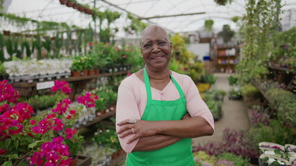 Obraz premium A Brazilian Florist standing inside local business Flower Shop and crossing arms smiling at camera. Cheerful older experienced employee staff