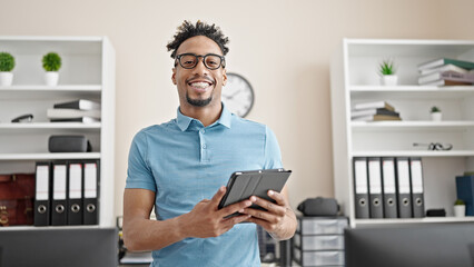 Obraz na płótnie Canvas African american man business worker smiling confident using touchpad at office