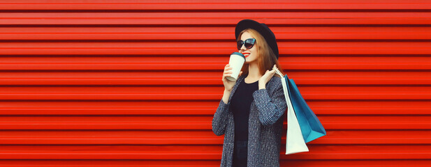 Portrait of happy smiling young woman with shopping bags and cup of coffee wearing blazer, black...