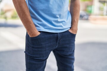 Young man standing with hands on pockets at street