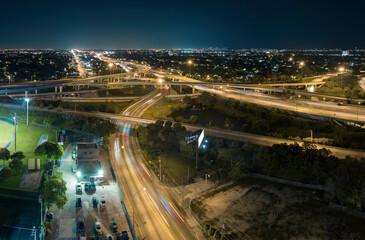 Fototapeta na wymiar View from above of american big freeway intersection in Miami, Florida at night with fast moving cars and trucks. USA transportation infrastructure concept