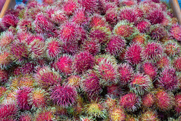 A pile of fresh tasty, ripe rambutan fruits on a market stand