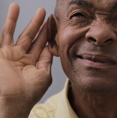 Obraz premium deaf man suffering from deafness and hearing loss on grey background with people stock photo