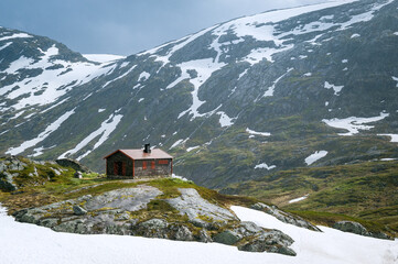 Fototapeta na wymiar Snowing weather and small house at rocks. Dalsnibba mountain plateau, Norway