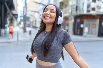 Young arab woman listening to music and breathing at street